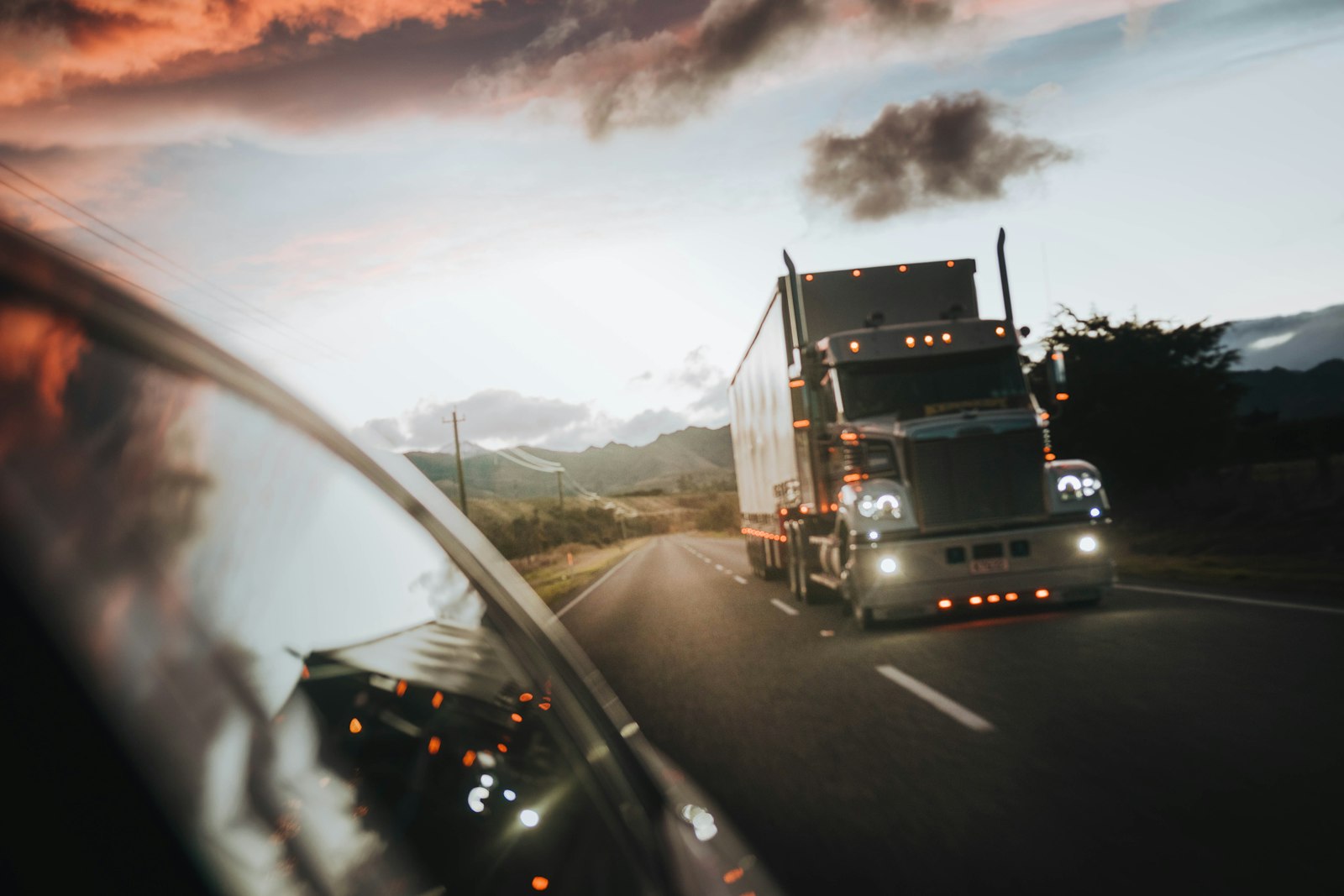 A semi truck driving on a highway at dusk