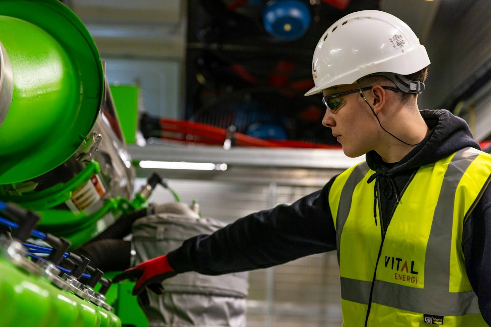 Worker in a hard hat and safety vest operating manufacturing machinery